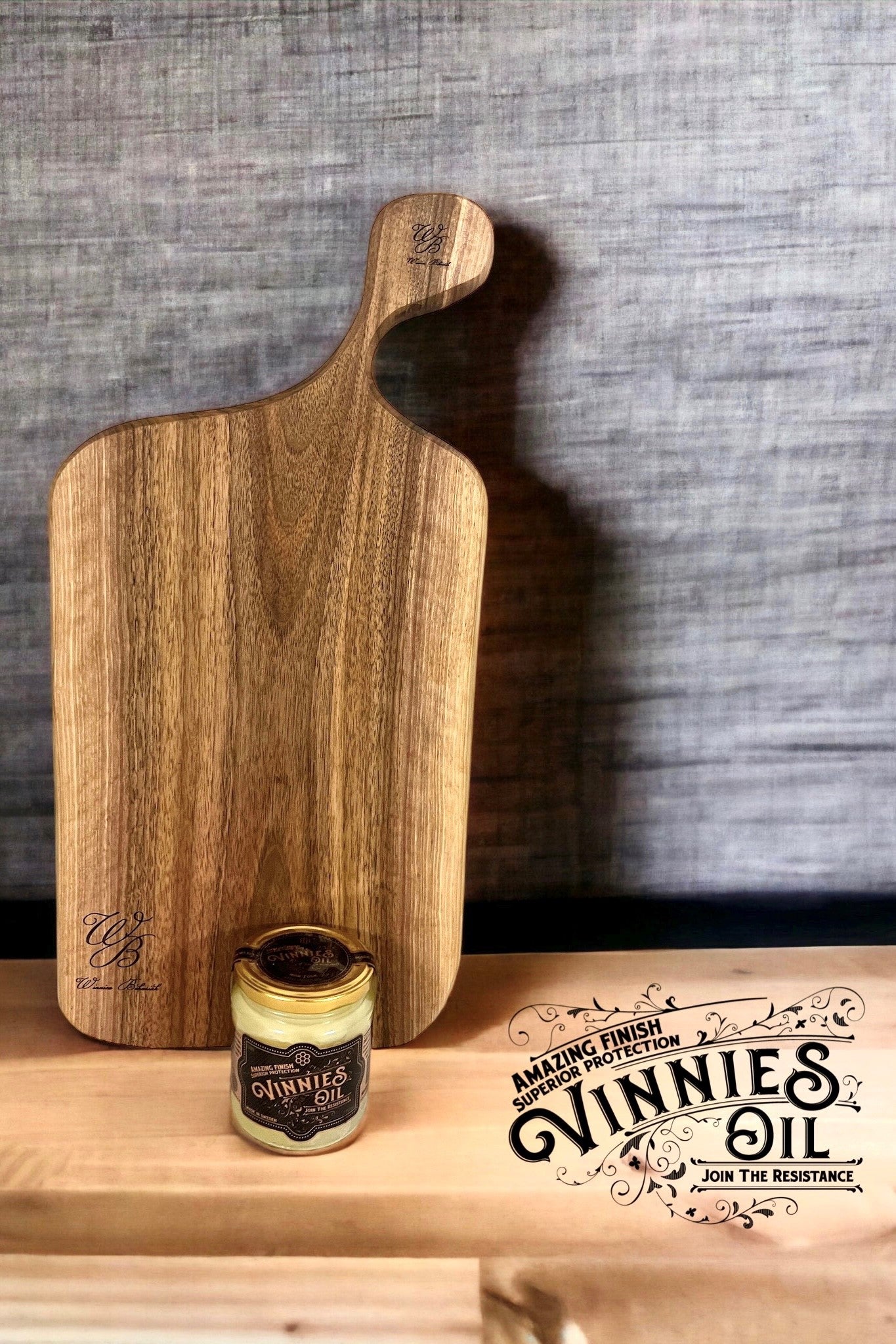 Wooden cutting board with a jar of Vinnie's Oil on a wooden surface.