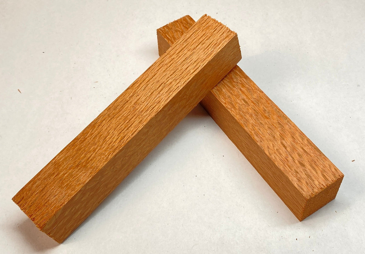 Two small rectangular wooden blocks with visible grain, arranged in a V shape on a plain off-white background.