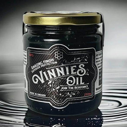 Jar of Vinnie's Oil with a decorative label on a reflective surface
